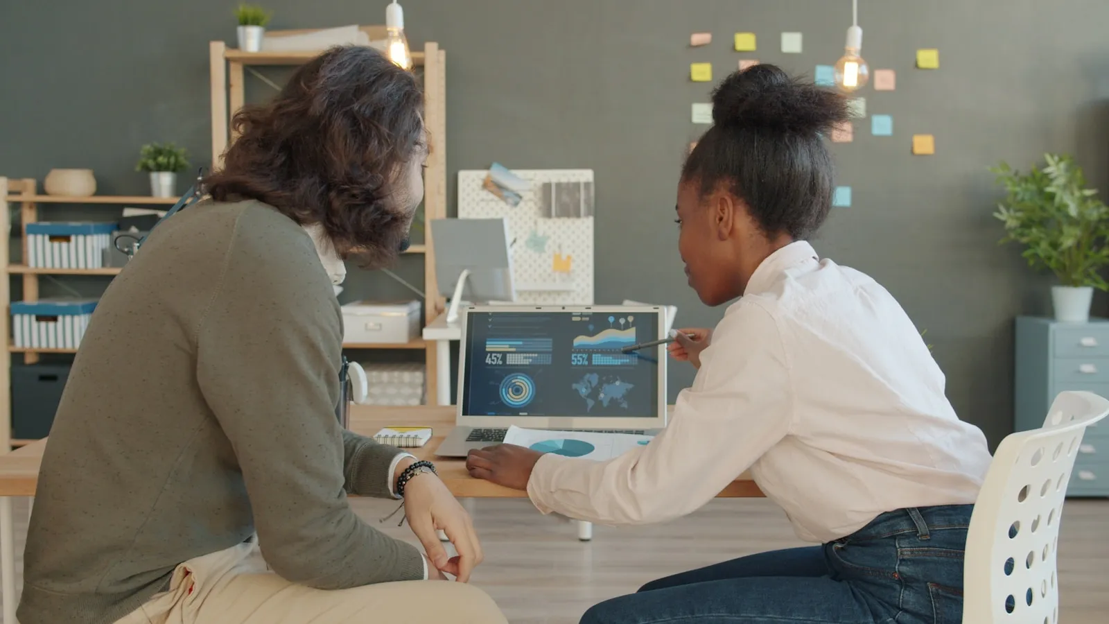Two colleagues reviewing data on a laptop in an office