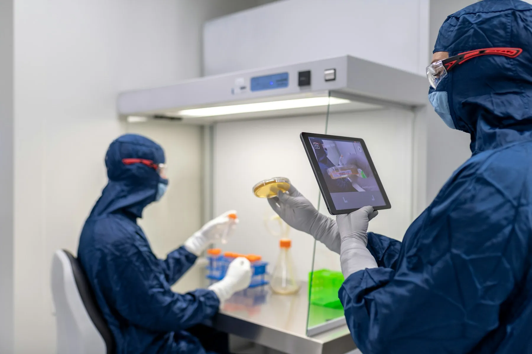 Cleanroom technicians working with lab samples and a tablet